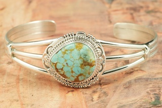 Genuine Number 8 Turquoise set in Sterling Silver Bracelet. Created by Navajo Artist John Nelson. Signed by the artist. The Number 8 mine is located in Eureka County Nevada. Since 1976 there has been no Number 8 Turquoise mined. There is however, an existing stock pile that Mr. Dowell Ward, the last owner of the Number 8 mine, had stocked away for later sorting. The Turquoise is a collector's item--because once the reserve is gone there will be no more material released onto the market. The Gold Mining Company owns the claim to the Number 8 mine and it has been swallowed up by the gold mining operations. This is some of the last Number 8 Turquoise to be had and will be a great addition to your collection. 